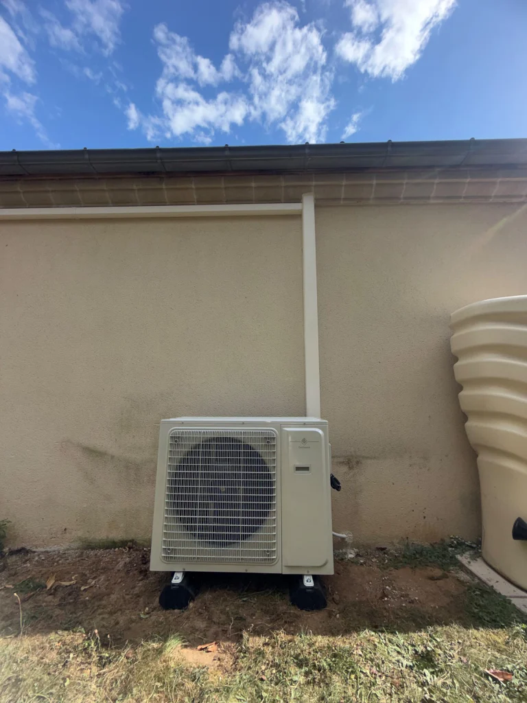 Groupe extérieur de climatisation au sol sur plots contre une façade de pavillon, goulotte peinte, climaticien Île-de-France