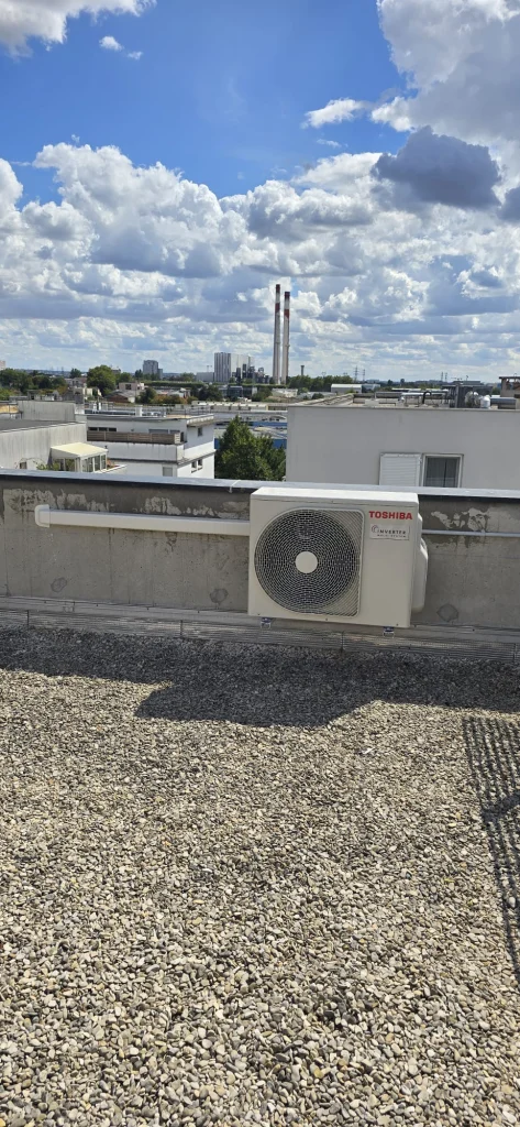 Groupe extérieur de climatisation posé sur une toiture-terrasse gravillonnée d'immeuble, climaticien Île-de-France