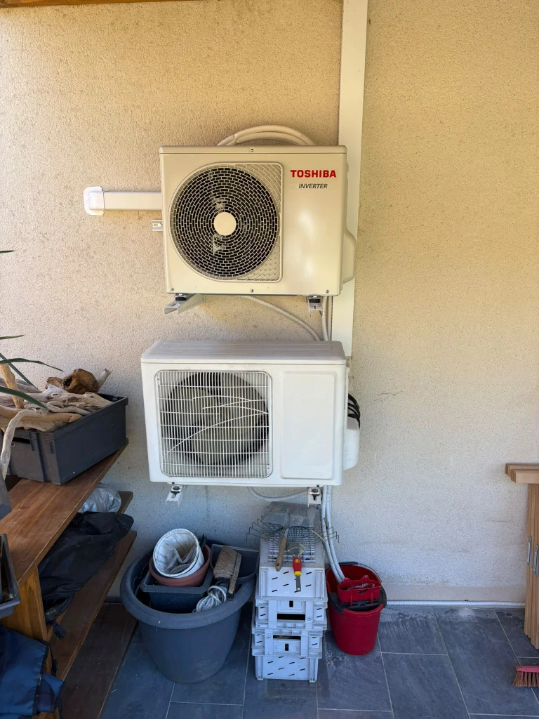 Deux groupes extérieurs Toshiba superposés, l'un au sol et l'autre sur support mural, sous un auvent, climaticien Île-de-France