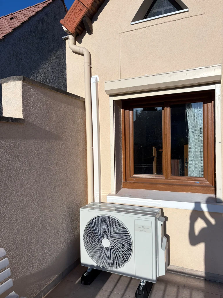 Groupe extérieur de climatisation sur une terrasse sous une fenêtre en bois, climaticien Île-de-France
