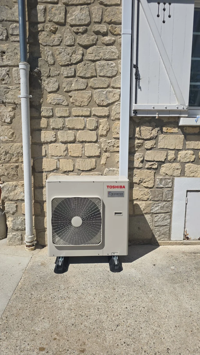 Groupe extérieur de climatisation Toshiba au sol devant une façade en meulière, climaticien Île-de-France
