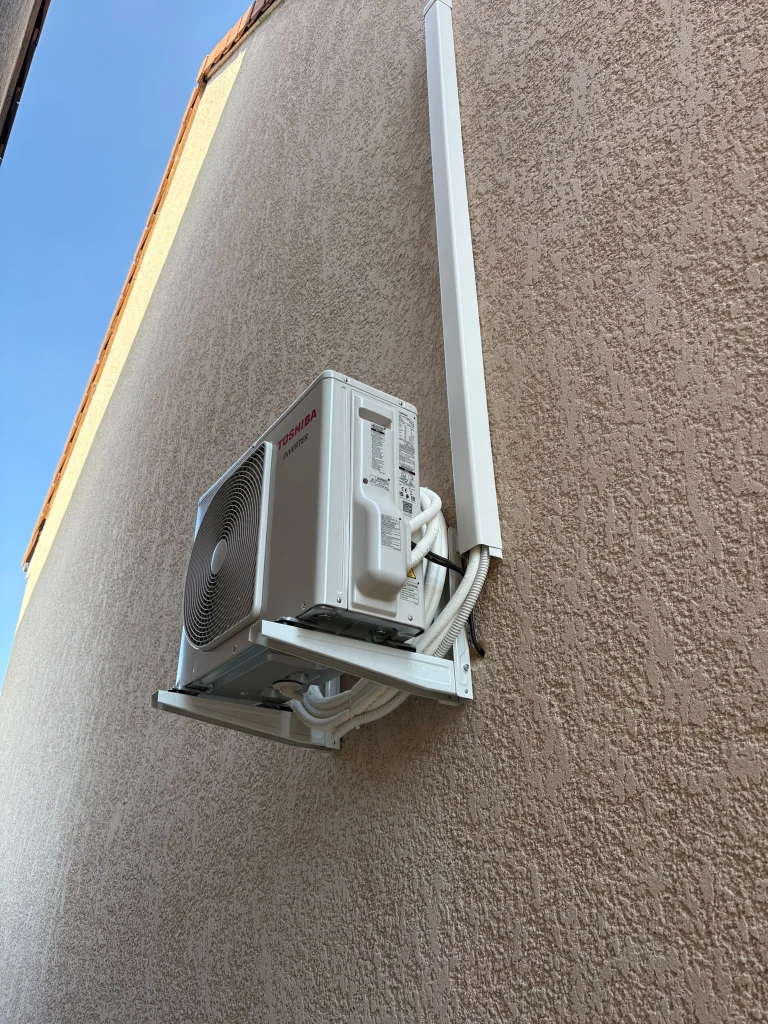 Groupe extérieur Toshiba sur support mural en pignon crépi avec goulotte verticale, climaticien Île-de-France