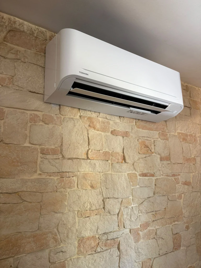 Split mural de climatisation fixé sur un mur en pierres de parement, climaticien Île-de-France