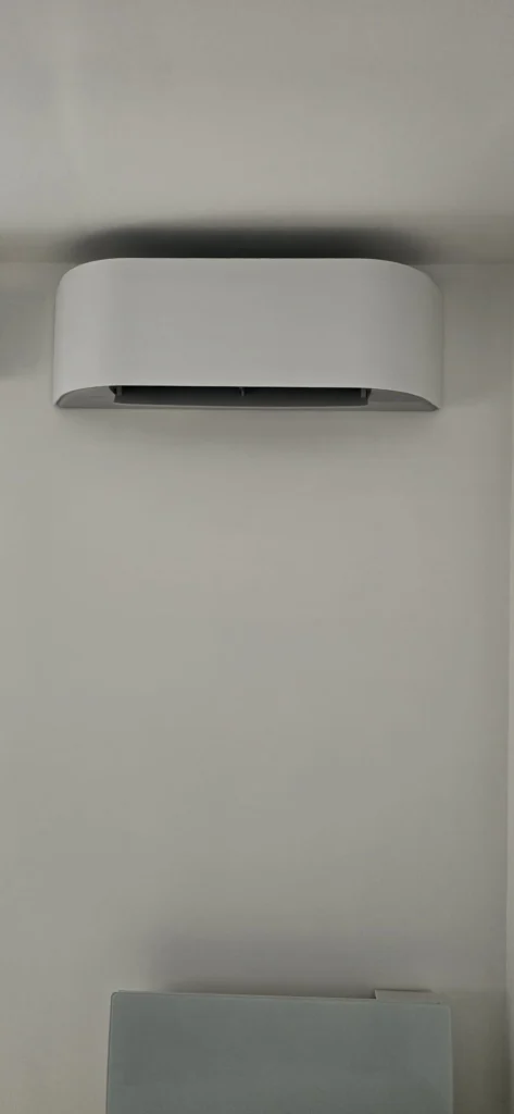Unité intérieure de climatisation au design arrondi sur un mur blanc, climaticien Île-de-France