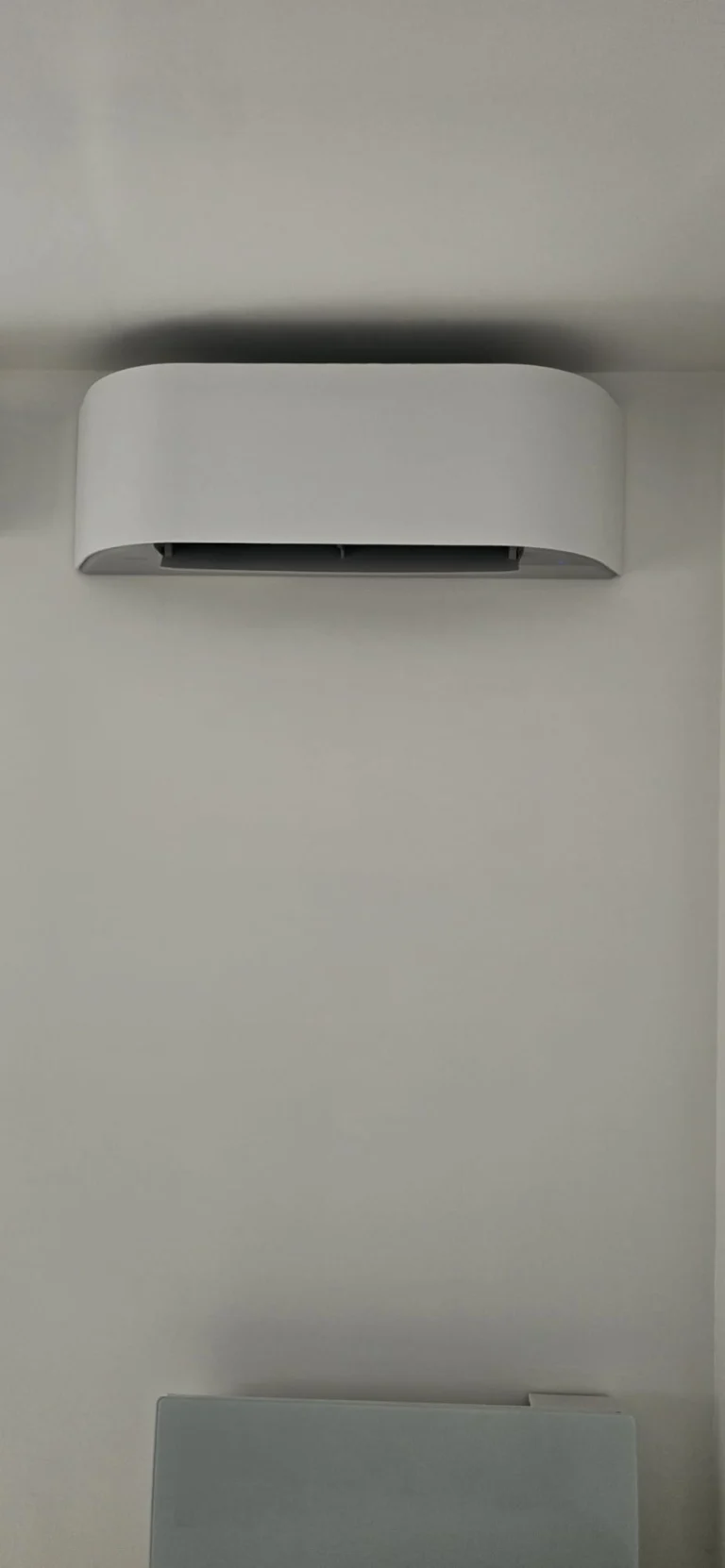 Unité intérieure de climatisation au design arrondi sur un mur blanc, climaticien Île-de-France