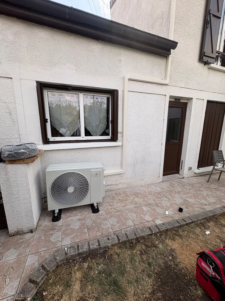 Groupe extérieur de climatisation au sol le long d'une allée pavée de pavillon, climaticien Île-de-France