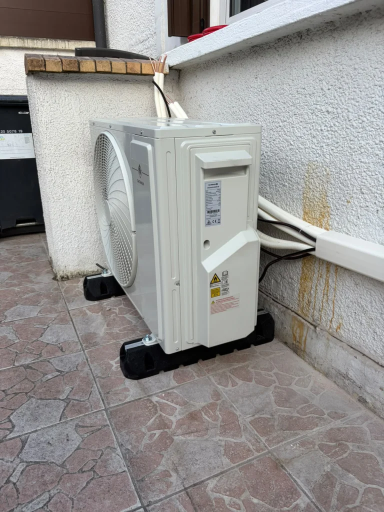 Groupe extérieur de climatisation sur une terrasse carrelée avec goulotte murale, climaticien Île-de-France