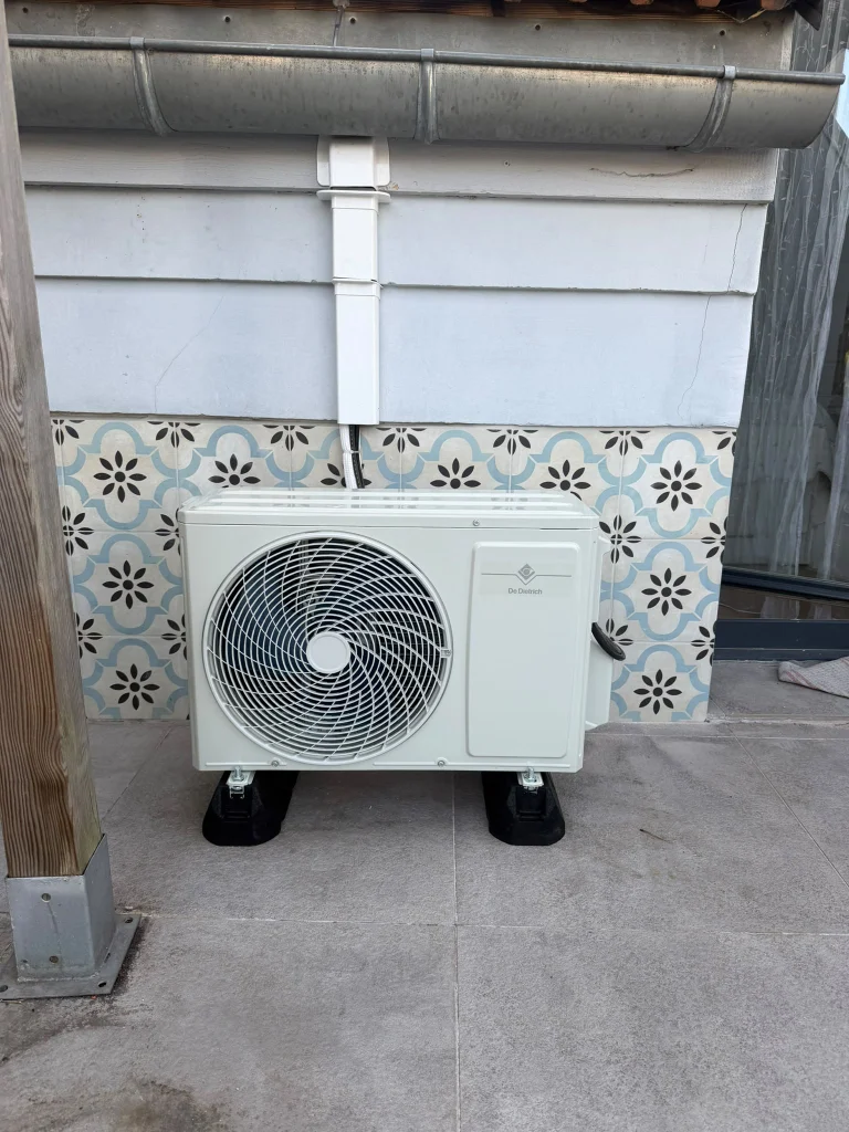 Groupe extérieur de climatisation sur une terrasse en carreaux de ciment, liaisons passées sous les tuiles, climaticien Île-de-France