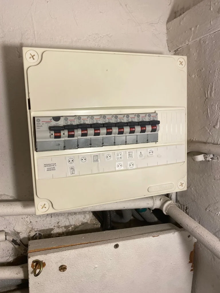 Tableau électrique d'ancienne génération sans différentiel 30 mA dans un sous-sol, avant remplacement par un électricien Île-de-France