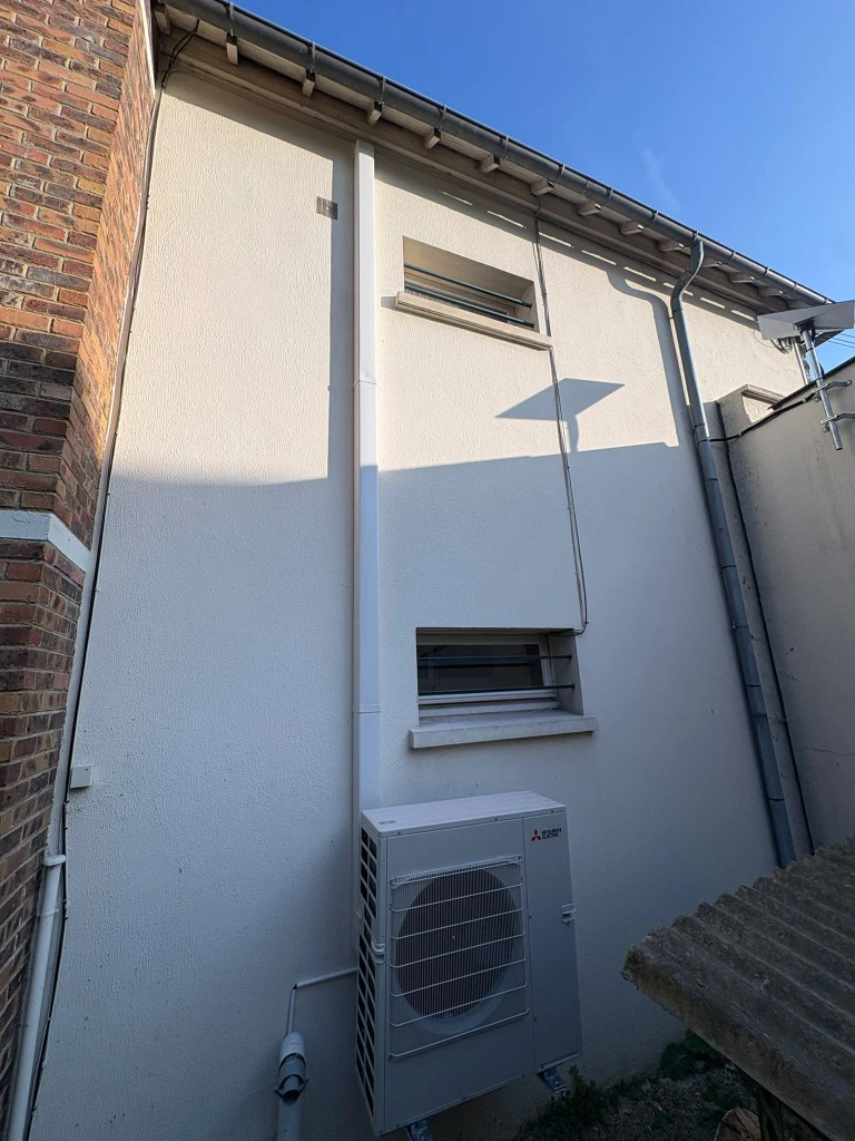 Groupe extérieur de climatisation au sol avec liaison longue en goulotte descendant de l'étage, climaticien Île-de-France
