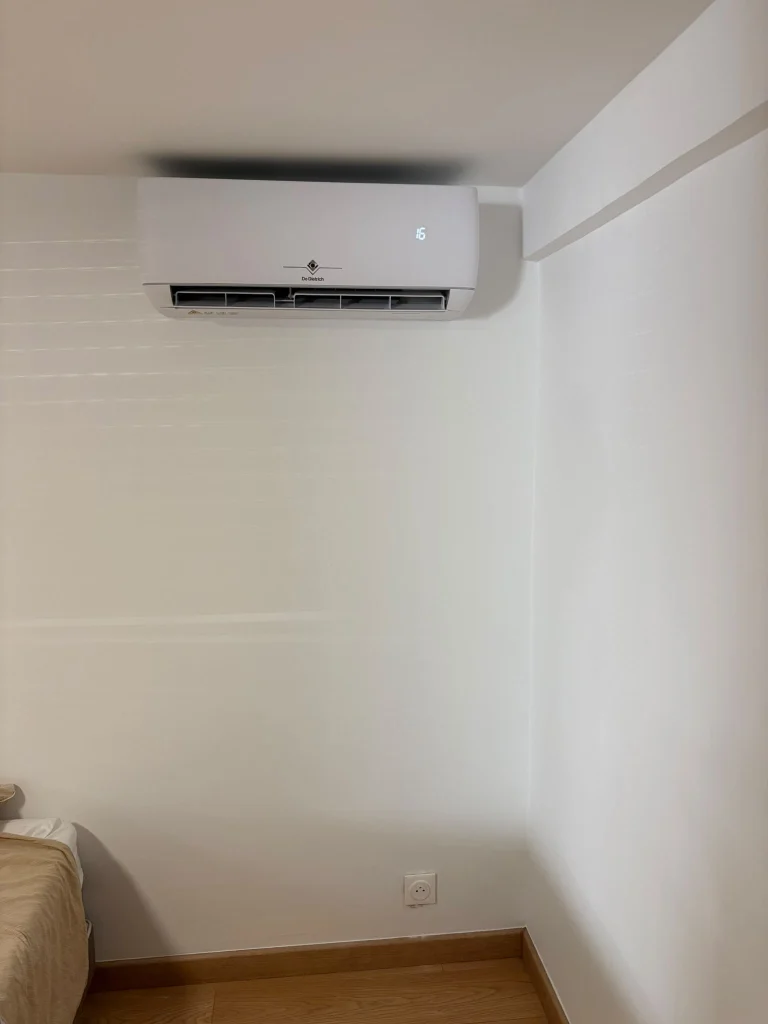 Split mural de climatisation au-dessus d'une porte dans une pièce parquetée, climaticien Île-de-France