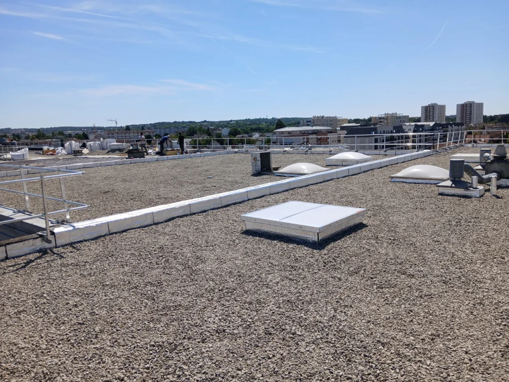 Toiture-terrasse d'immeuble refaite en bitume bicouche sous gravillons avec lanterneaux, étancheur Île-de-France