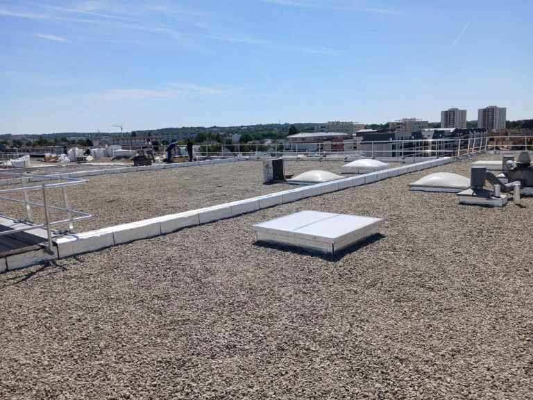 Toiture-terrasse d'immeuble refaite en bitume bicouche sous gravillons avec lanterneaux, étancheur Île-de-France