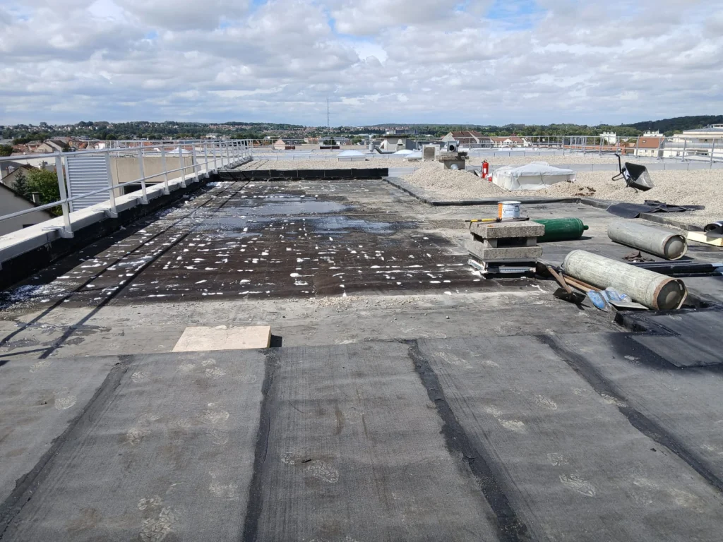 Toiture-terrasse d'immeuble refaite en bitume bicouche sous gravillons avec lanterneaux, étancheur Île-de-France