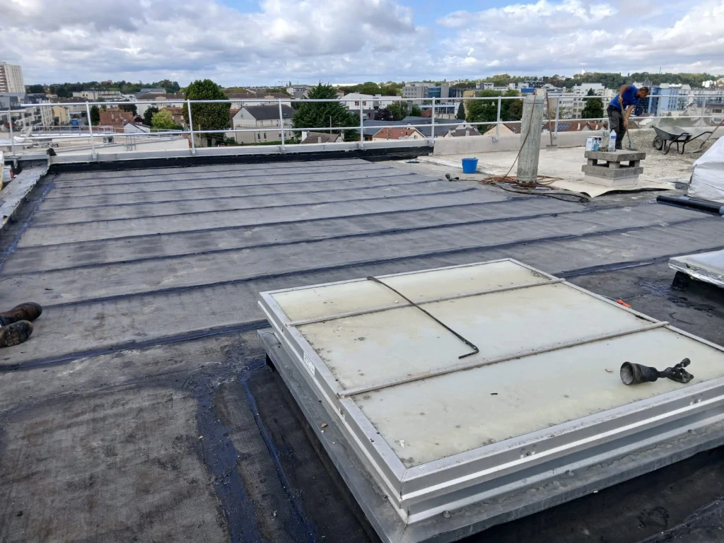 Toiture-terrasse d'immeuble refaite en bitume bicouche sous gravillons avec lanterneaux, étancheur Île-de-France