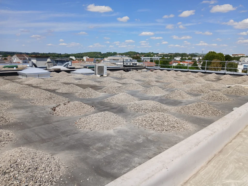 Toiture-terrasse d'immeuble refaite en bitume bicouche sous gravillons avec lanterneaux, étancheur Île-de-France
