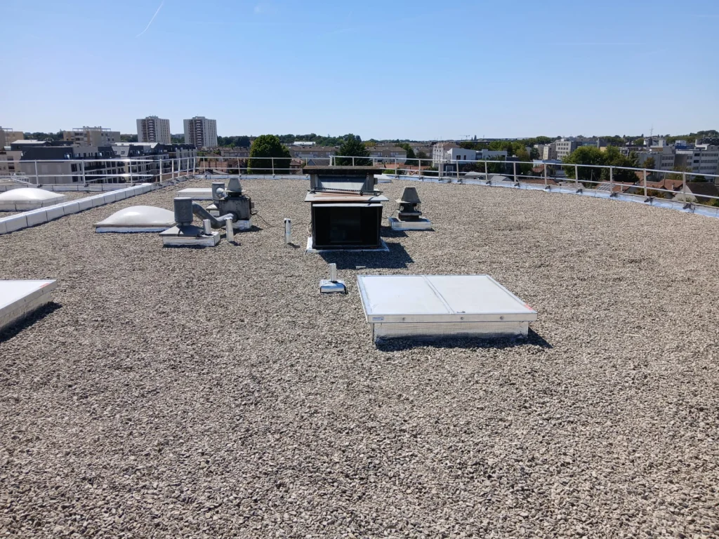 Toiture-terrasse d'immeuble refaite en bitume bicouche sous gravillons avec lanterneaux, étancheur Île-de-France