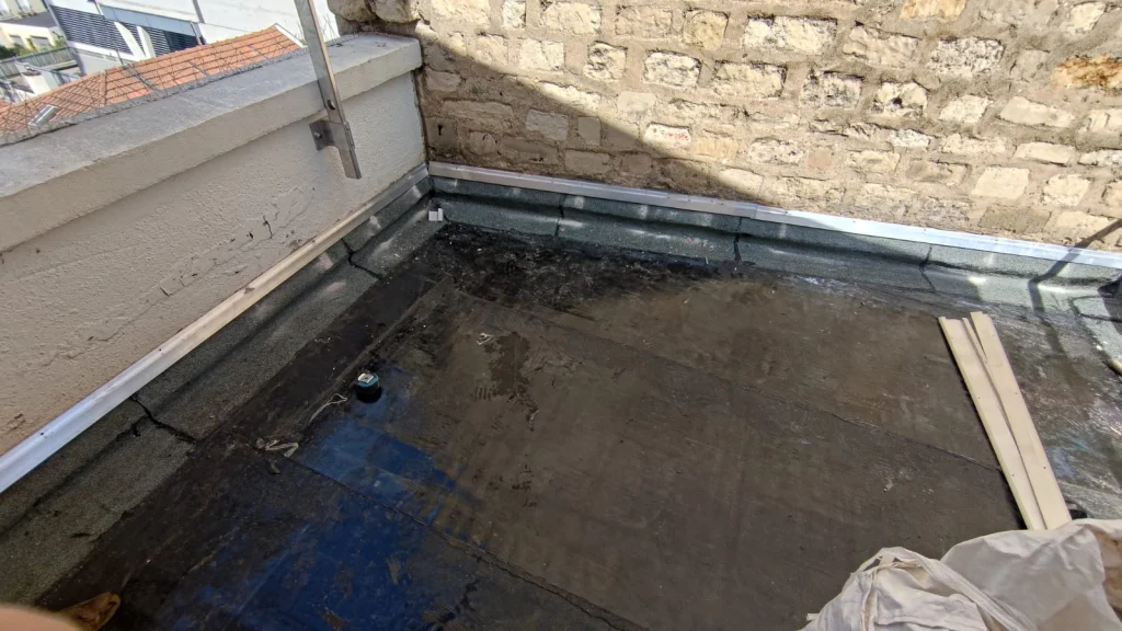 Petite terrasse entre murs en pierre avec relevé d'étanchéité et bande de rive refaits, étancheur Île-de-France