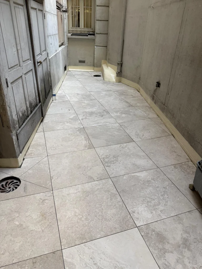 Terrasse d'appartement carrelée en travertin sur une étanchéité neuve avec siphon de sol, étancheur Île-de-France