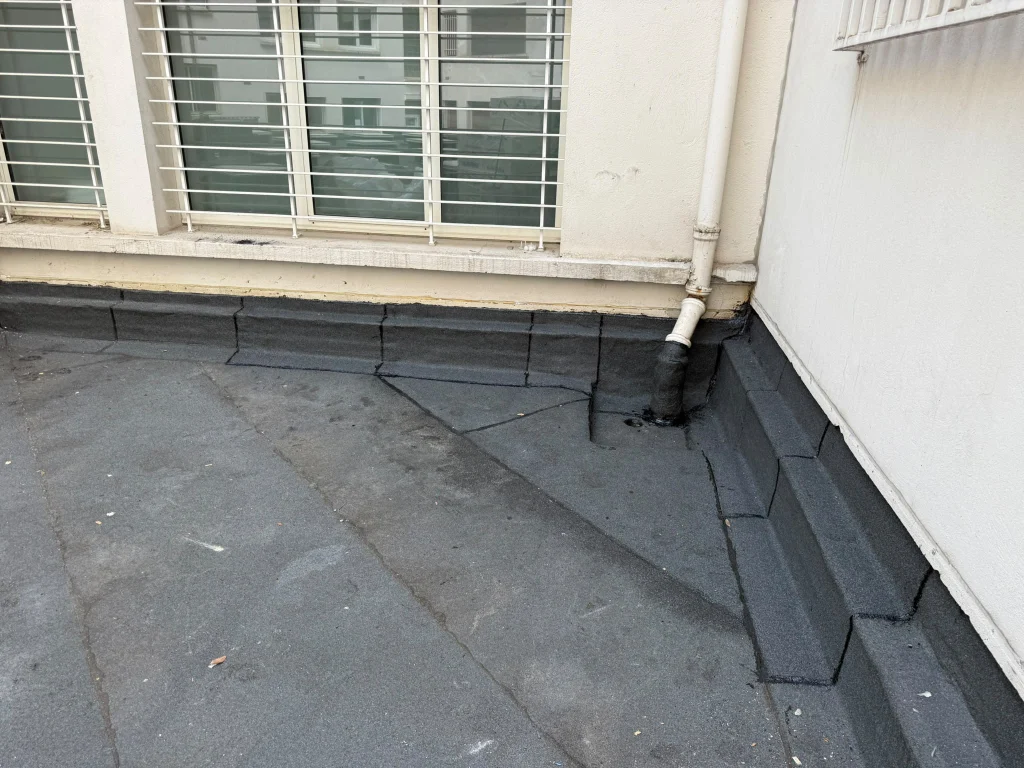 Relevés d'étanchéité bitume au pied d'un brise-soleil et dans les angles d'une terrasse d'immeuble, étancheur Île-de-France