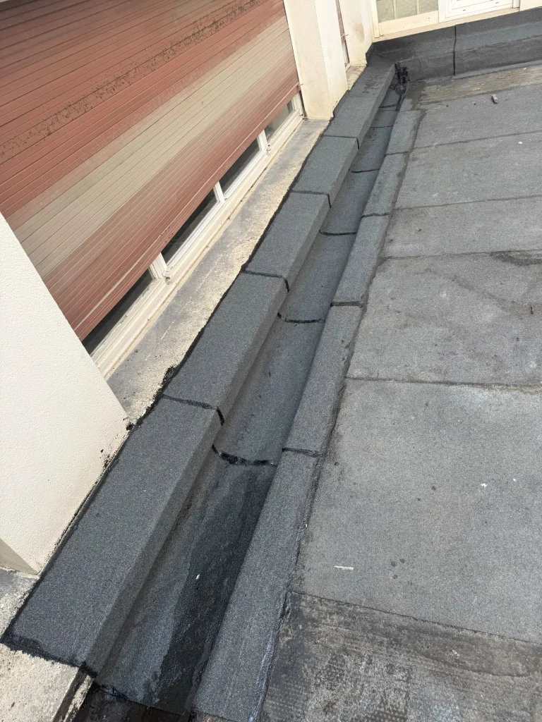 Relevés d'étanchéité bitume au pied d'un brise-soleil et dans les angles d'une terrasse d'immeuble, étancheur Île-de-France