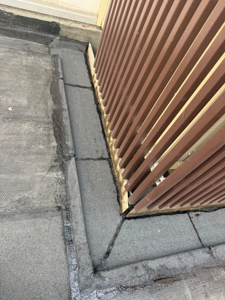 Relevés d'étanchéité bitume au pied d'un brise-soleil et dans les angles d'une terrasse d'immeuble, étancheur Île-de-France