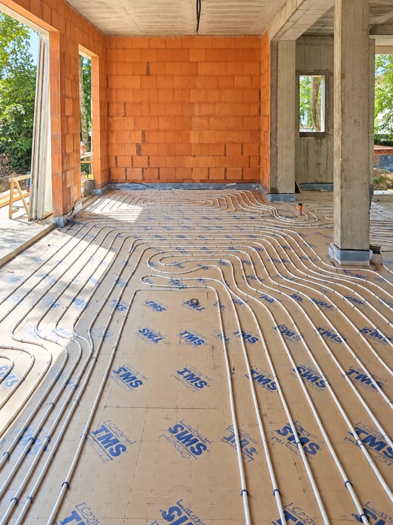 Tubes de plancher chauffant posés en serpentin sur isolant dans une maison en construction, installation de plancher chauffant Île-de-France