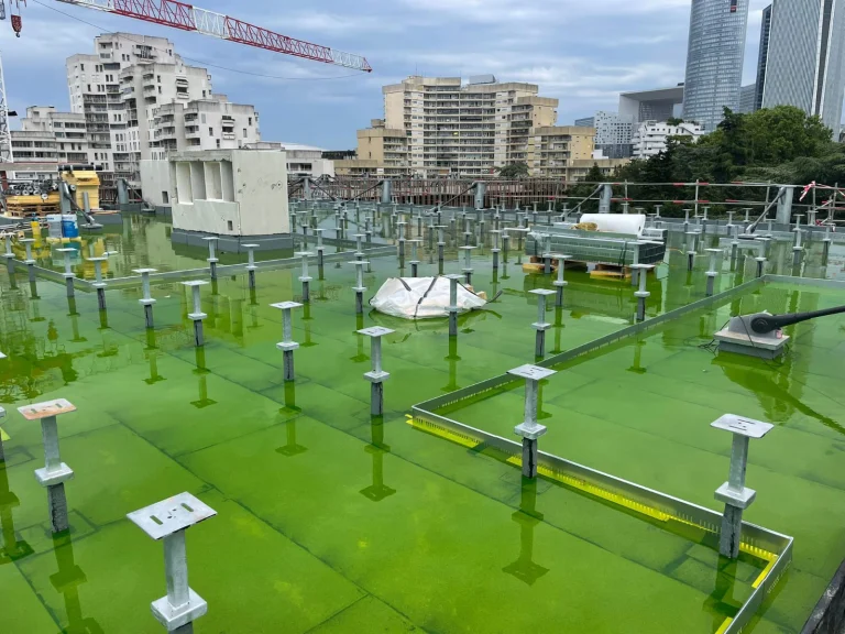 Grande toiture-terrasse neuve en mise en eau colorée avant pose des dalles sur plots, étancheur Île-de-France