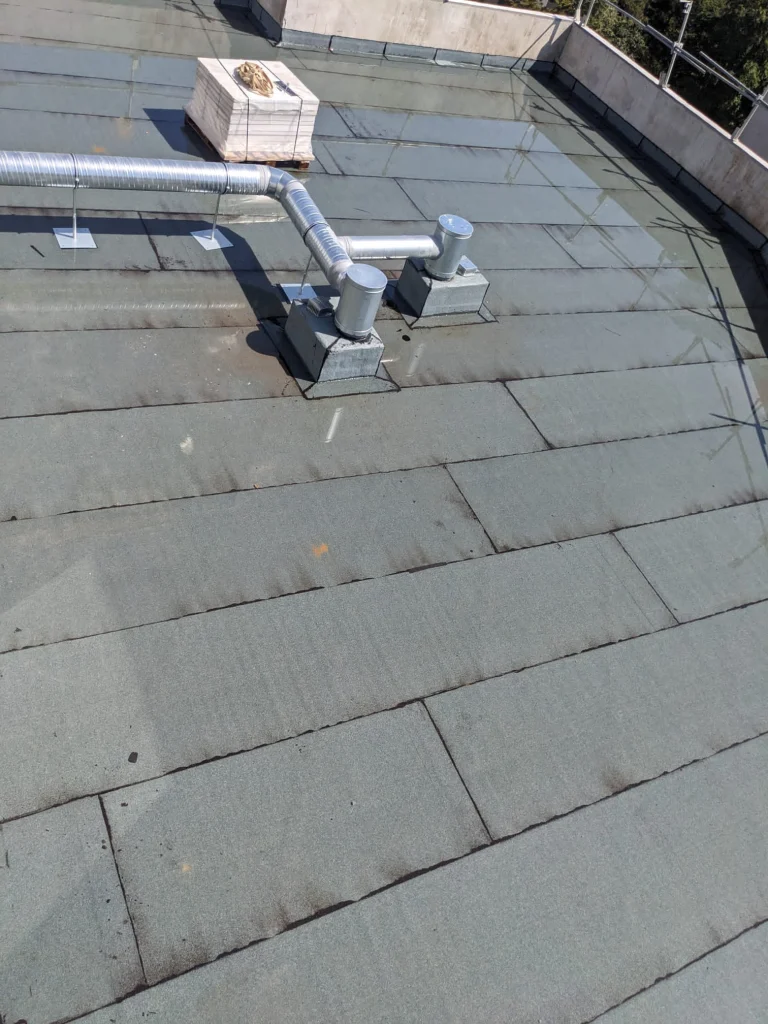 Toiture-terrasse de bâtiment collectif en bitume ardoisé avec sorties de ventilation traitées, étancheur Île-de-France